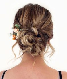 the back of a woman's head with flowers in her hair, wearing a black tank top