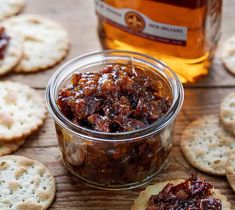 a glass jar filled with jam next to crackers