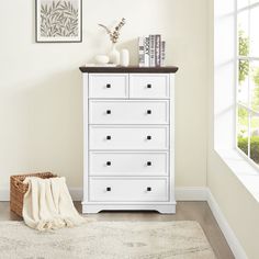 a white dresser sitting in a room next to a window with a rug on the floor