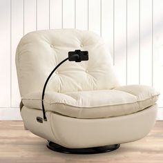 a white leather reclining chair sitting on top of a hard wood floor next to a wall