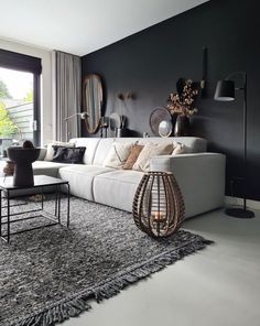 a living room with black walls and white furniture in the center, along with an area rug on the floor