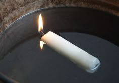 a lit candle sitting in a black pan