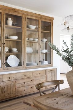 a wooden cabinet with glass doors and dishes on it's sides in a dining room