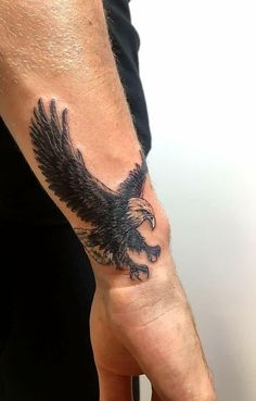 a man's arm with an eagle tattoo on the left side of his hand