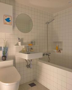 a white tiled bathroom with a sink, toilet and bathtub