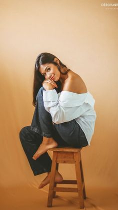 a woman sitting on top of a wooden stool