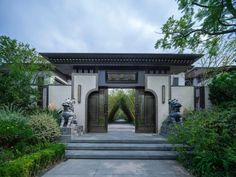 an entrance to a home surrounded by greenery and stone steps with statues on either side