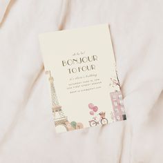 an open book on top of a bed with the eiffel tower in the background