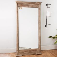 a mirror sitting on top of a wooden floor next to a plant