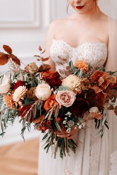 a woman in a wedding dress holding a bouquet with flowers on it's side