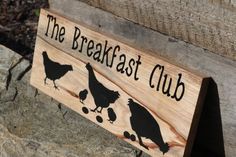 a wooden sign that says the breakfast club with chickens and cherries hanging from it