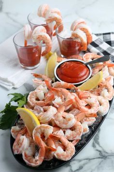 a platter filled with shrimp, lemon wedges and ketchup on a marble table