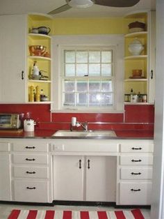 a kitchen with red and white striped rug on the floor, yellow walls and cabinets