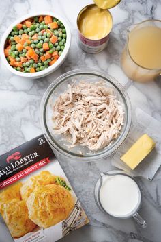 ingredients to make chicken pot pie laid out on a marble counter top with milk, eggs, butter, and other foodstuffs