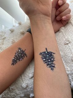 two people with matching tattoos on their arms, one has a pine cone and the other has a star