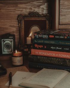 a stack of books sitting on top of a wooden table next to a phone and camera