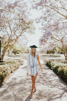 a woman walking down a path wearing a graduation cap