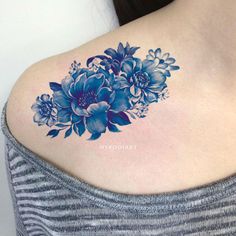 a blue flower tattoo on the back of a woman's upper arm and shoulder