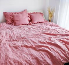 a bed with pink linens and pillows on it