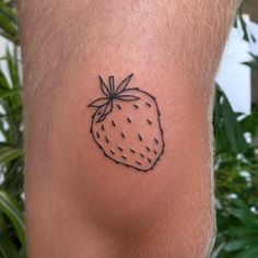 a small strawberry tattoo on the back of a man's left leg, which is black and white