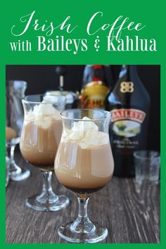 two glasses filled with ice cream sitting on top of a wooden table next to bottles