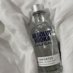 an empty vodka bottle sitting on top of a white bed sheet with the words absolut vodka printed on it