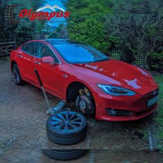 a red car parked in front of a fence