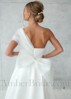 a woman in a white dress with a big bow on her back