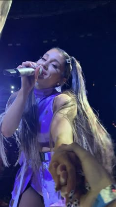 a woman with long hair singing into a microphone