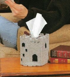 a person sitting on a couch reading a book and holding a tissue paper in their hand