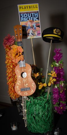 a ukulele sitting on top of a table next to flowers and a hat