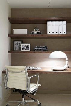 a white office chair sitting in front of a desk with a lamp and books on it