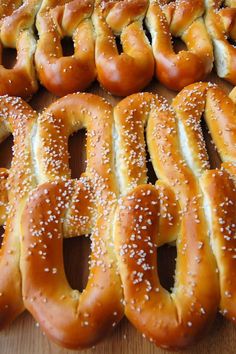 several pretzels are lined up on a wooden table with sesame seed sprinkles