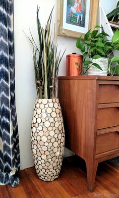 there is a vase on the floor next to a dresser and some plants in it