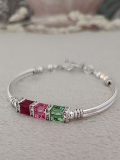 This family birthstone bracelet is the perfect way to celebrate Mother's Day. This could be gifted to Mom, Grandma, daughter, friend, or anyone in your life that's special to you. Birthstone jewelry represents family, and family is one of the most precious things in life!  ABOUT THIS ITEM: * 6mm austrian crystals * sliver rhinestone squaredelles * silver plated tube beads * pewter toggle clasp * rose, peridot and ruby crystals are used in the photos above PURCHASING OPTIONS: * birthstone months Ruby Crystal, Birthstone Bracelet, Personalized Gifts For Mom, Mom And Grandma, Birthstone Bracelets, Tube Beads, Bracelet For Women, Toggle Clasp, Bridesmaids Gifts