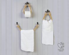 two white towels hanging on the wall next to a toilet paper roll and towel rack