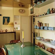 a dining room table with plates and bowls on the shelves above it, next to a doorway