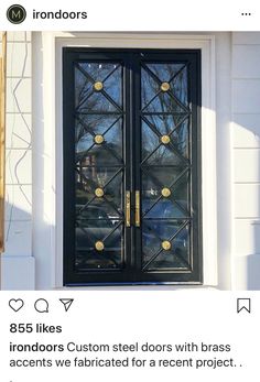 a black double door with gold knobs on the side of a white house in winter