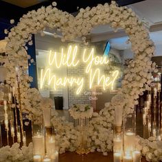 a heart shaped mirror with candles and flowers on it that says will you marry me?