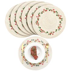 four plates and six place mats with holly designs on them, one has a piece of broccoli in the middle