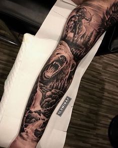 a man's arm with a bear and wolf tattoo on the left side of his arm