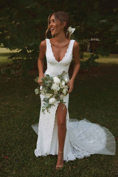 a woman in a white dress holding a bouquet and posing for the camera with her legs crossed