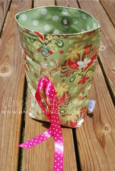 a cup with a pink ribbon tied to it sitting on a wooden table next to a bottle opener