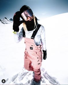 a woman wearing skis and goggles standing in the snow with her back to the camera