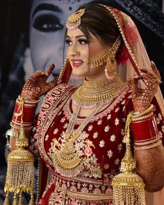 a woman in a red and gold bridal outfit holding her hands up to her face