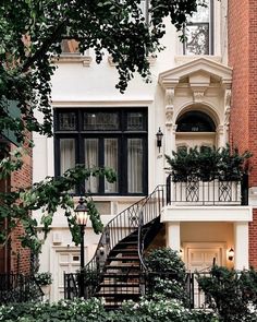 an apartment building with stairs leading up to the front door and second story windows on either side