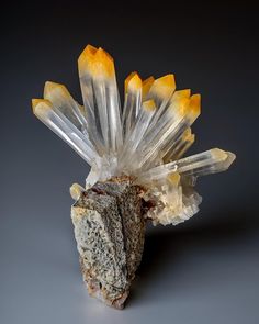 a crystal cluster with yellow and white crystals on it's end, in front of a black background