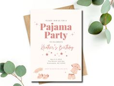 a pink baby shower party card with leaves and greenery on the table next to it