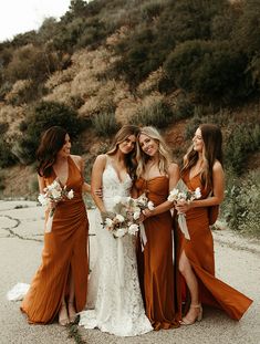 four bridesmaids pose for a photo in front of a mountain side with their bouquets