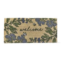 a welcome mat with blue flowers and green leaves on the front, which reads'welcome '